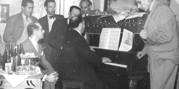 Benigno Ballón Farfán tocando el piano entre amigos y familiares en su sala de ensayo.