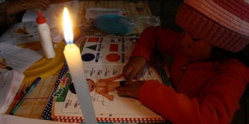 Tres hermanitos estudian a la luz de la vela porque la carga del panel se agotó.